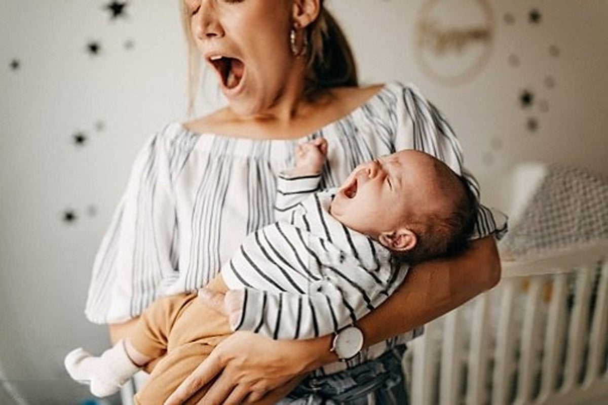 Maman épuisée qui bâille, bébé en pleurs dans les bras